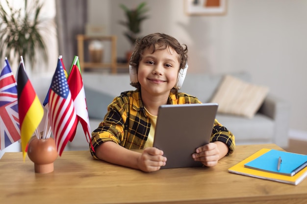 Internationaal onderwijs voor kinderen Schattige kleine jongen met hoofdtelefoon die geniet van online les op digitale tablet