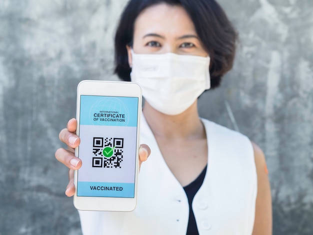 Certificato internazionale di vaccinazione, passaporto digitale intelligente con codice qr sullo schermo dello smartphone. donna asiatica vaccinata con cerotto che mostra il passaporto sanitario della certificazione di vaccinazione.