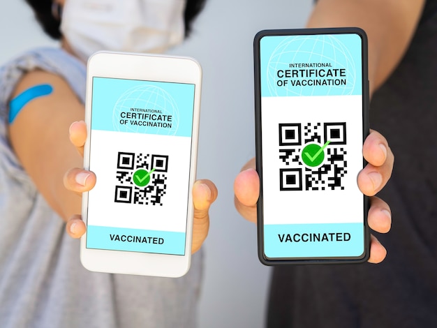 Международный сертификат вакцинации, умный цифровой паспорт с QR-кодом на экране смартфона. Вакцинированные мужчина и женщина в маске с паспортом здоровья и свидетельством о вакцинации.