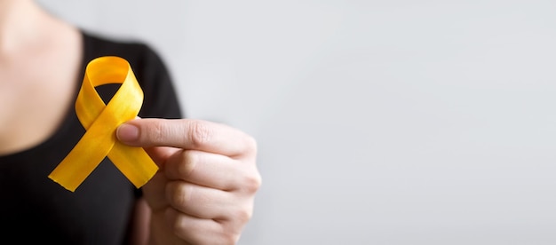 Photo international childhood cancer day woman holding yellow ribbon leukemia cancer awareness