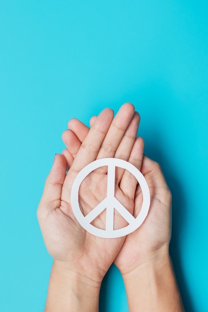 International Day of Peace Hands holding white paper Peace symbol on blue background Freedom Hope World Peace day 21 September and Nuclear Disarmament concepts