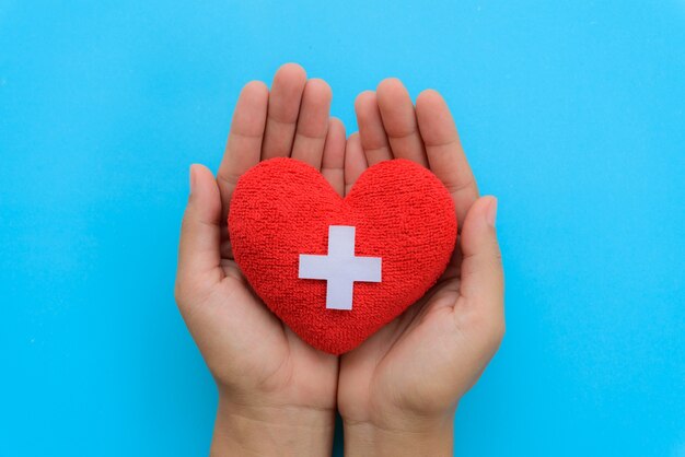 Foto giorno internazionale degli infermieri, mano della donna che tiene cuore rosso su fondo blu.