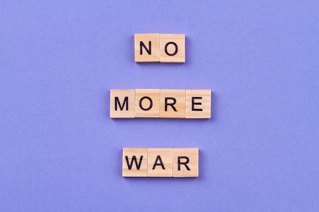 Концепция международного мира. Слоган «Нет больше войны», написанный буквами на деревянных кубиках. Изолированные на синем фоне.