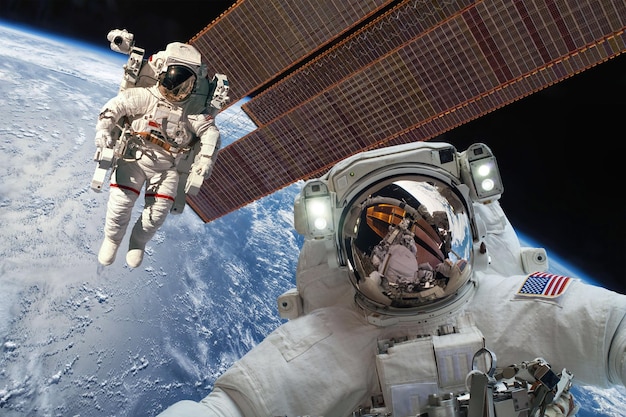 地球上の宇宙空間にいる国際宇宙ステーションと宇宙飛行士。 NASAによって提供されたこの画像の要素。