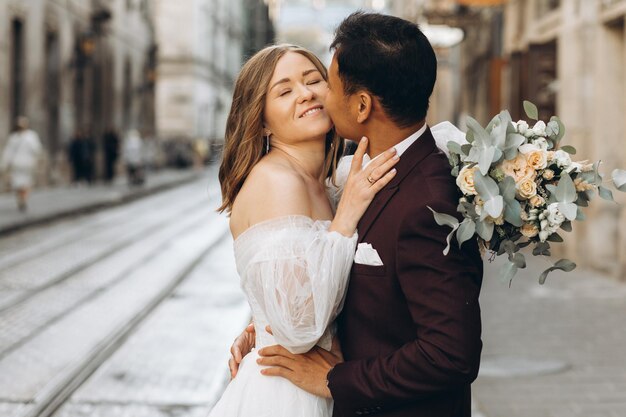 An international wedding couple a European bride and an Asian groom walk around the city together