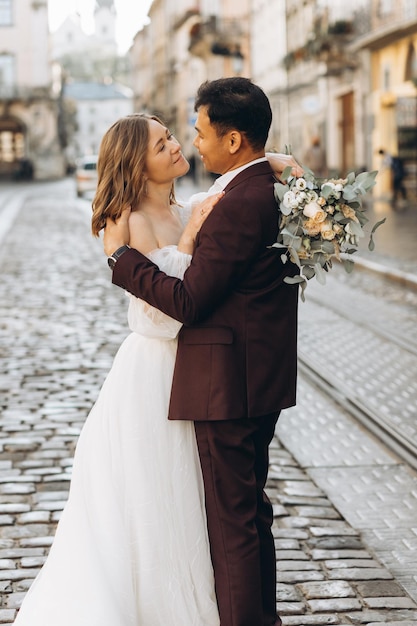 An international wedding couple a European bride and an Asian groom walk around the city together