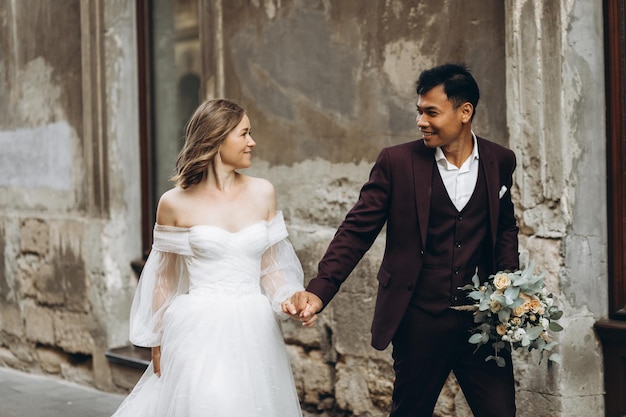 An international wedding couple a European bride and an Asian groom walk around the city together