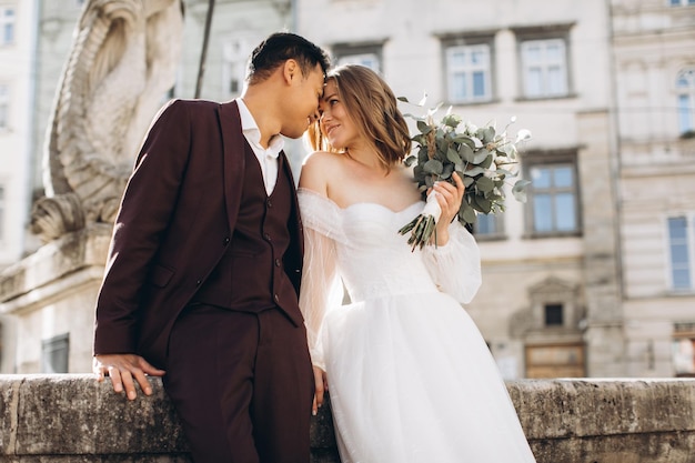 Una coppia di sposi internazionali, una sposa europea e uno sposo asiatico camminano insieme per la città