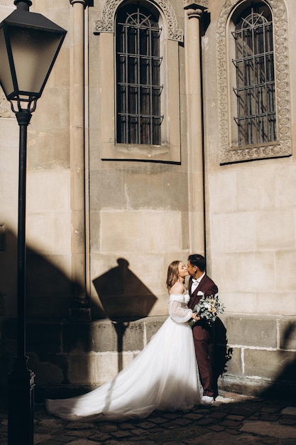 Photo an international wedding couple a european bride and an asian groom walk around the city together