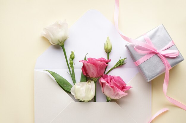 International Women's Day. Close-up envelope with eustomas, with a gift box, flat lay.