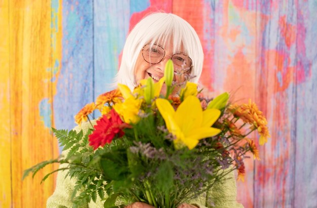 International Women's Day Extremely happy senior whitehaired woman holding a bouquet of spring flowers looking at camera smiling