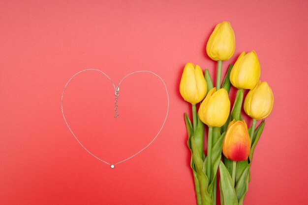 International Women's Day with flowers and heart shape necklace on red background