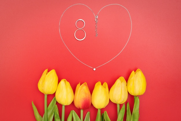 International Women's Day with flowers and heart shape necklace on red background