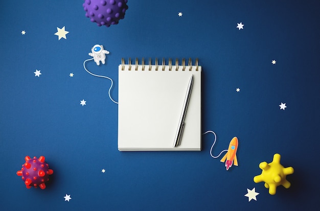 Internationale dag van de bemande ruimtevlucht. 12 april Wereldkosmonautiekdag. Spiraalvormig notitieboekje op samenvatting geïsoleerde blauwe muur. Cartoon galactisch concept.