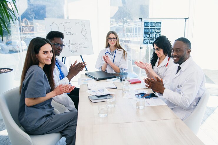 Internationale groep van professionele jonge artsen klappen in hun handen en glimlachen op een medische conferentie in een moderne kliniek