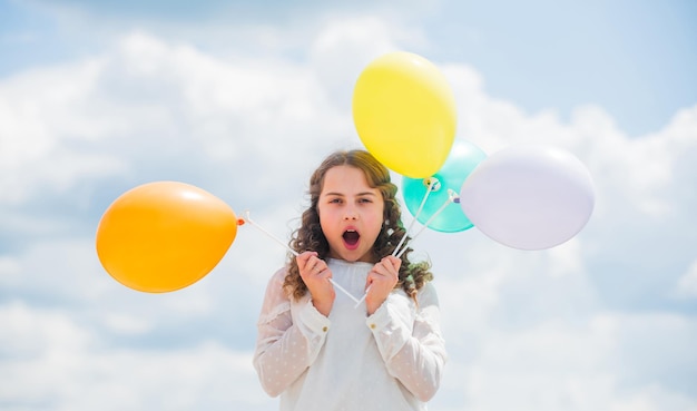 Internationale kinderdag. Gelukkig kind met kleurrijke luchtballonnen over blauwe hemelachtergrond. positieve emoties uiten. gewoon plezier hebben. vrijheid. zomervakantie viering.