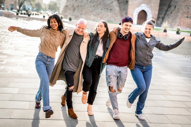 Internationale trendy vrienden die in het stadscentrum lopen en grappige, gekke bewegingen maken