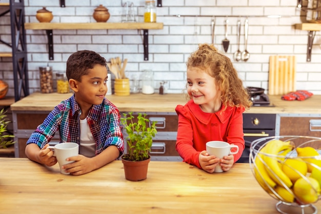 Internationale vriendschap. Schattig kind dat een glimlach op haar gezicht houdt terwijl ze in de keuken zit