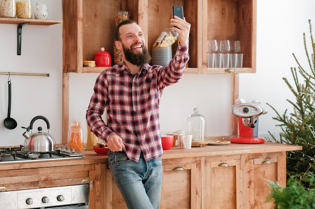 Internet communicatie. Vrolijke hipster man met app op smartphone om video-oproep te hebben.