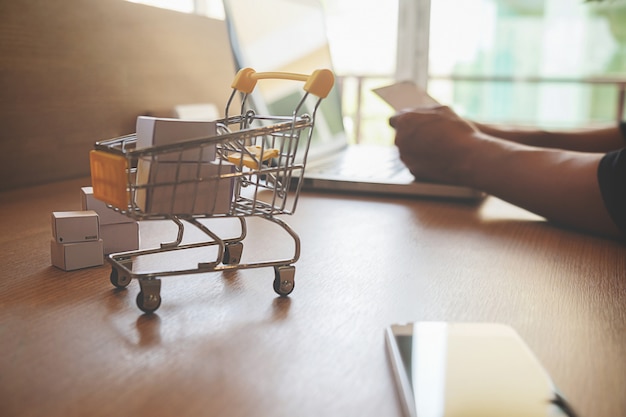 Internet online shopping concept with laptop and shopping-cart.Vintage tone retro filter effect, soft focus(selective focus)