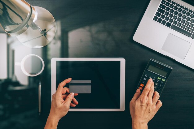 Internet shopping conceptTop view of hands working with laptop and credit card and tablet computer