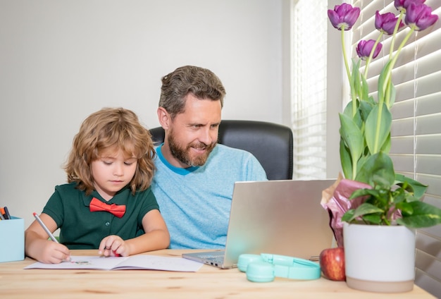 Navigare in internet padre e figlio usano il computer a casa blog di famiglia ragazzo fare i compiti