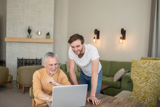 On internet. Two men in the room at the laptop watching something on a laptop