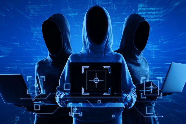 Internetbeveiliging en diefstal van persoonlijke gegevens concept met blauwe schaduwen gezichtsloze hackers in hoody met behulp van laptop en abstracte virtuele technologische symbolen