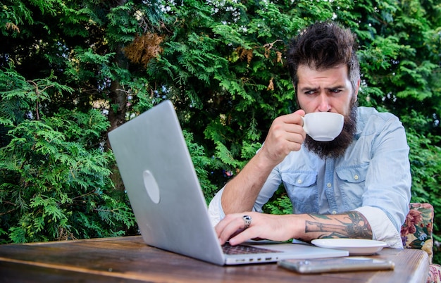 Internetcafé bezoeken. Hipster genieten van thee en gratis wifi in het buitencafé. Bebaarde man drinken en surfen op het web in café. Cybercafé met internettoegang en vers gezette koffie.