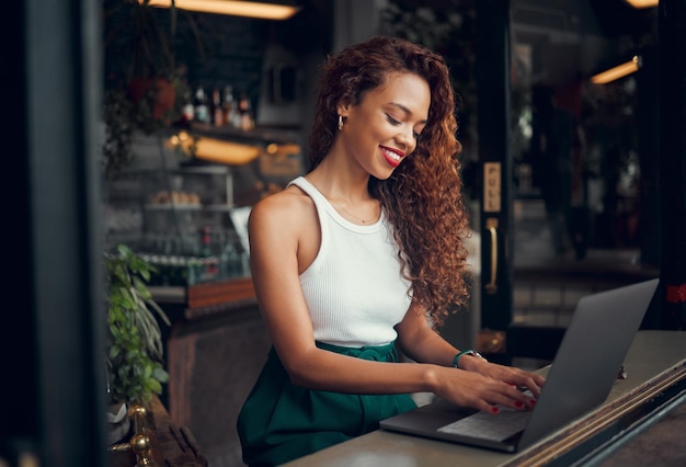 Internetcafé op laptop en typen met een zwarte blogger die aan het raam van een coffeeshop werkt aan een artikel of rapport Computer-e-mail en werken op afstand met een vrouwelijke schrijver die druk bezig is in een restaurant