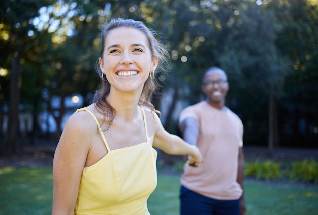 Interracial couple holding hands and park with happiness romance and bonding outdoor love or relationship Romantic woman and black man in nature joyful or touching hand on date and quality time