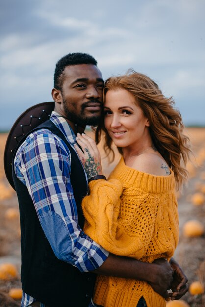 Interracial couple standing in a pumpkin field