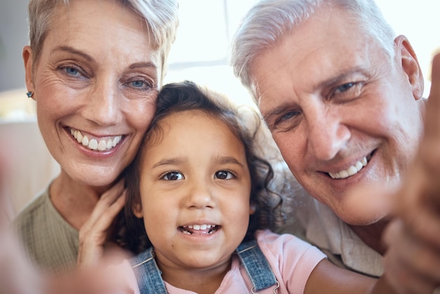 Interracial family selfie and girl with grandparents at home feeling happy with love and care Portrait of senior people with an adopted kid bonding together at a house busy with youth care