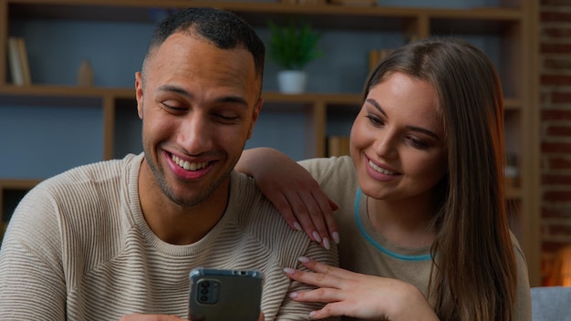 Interracial getrouwd paar echtgenoten multiracial etnische familie kijken naar mobiele telefoon scherm smartphone