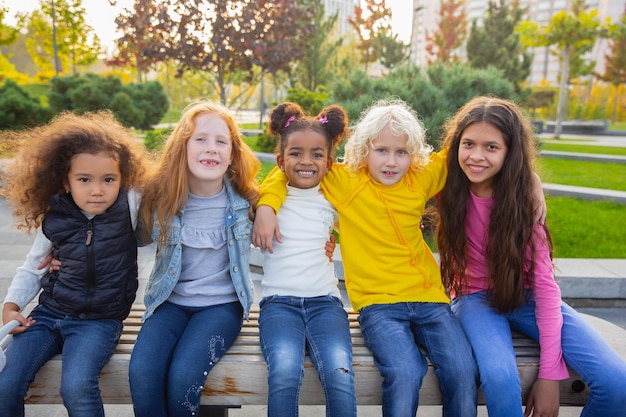 Gruppo interrazziale di bambini, ragazze e ragazzi che giocano insieme al parco in una giornata estiva