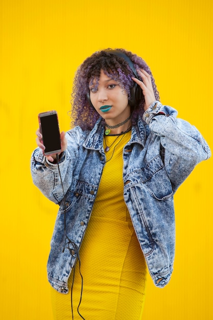 Interracial teenager listening to music on a yellow wall