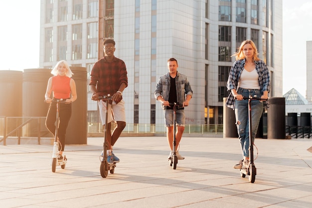 Interraciale groep vrienden rijden op elektrische scooters in de stad