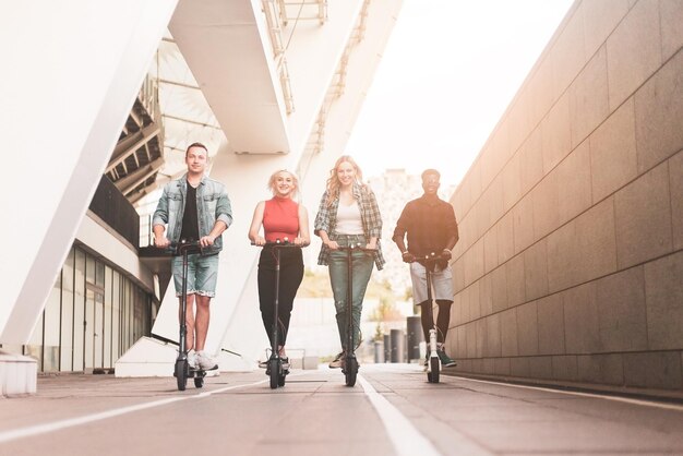 Interraciale groep vrienden rijden op elektrische scooters in de stad