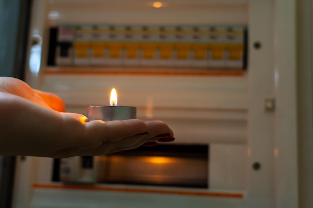 Interruptions in the supply of electricity, a woman's hand with a candle near the electric box