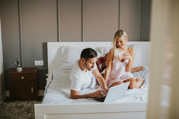 Intieme geliefden die laptop gebruiken die op het bed in de slaapkamer liggen