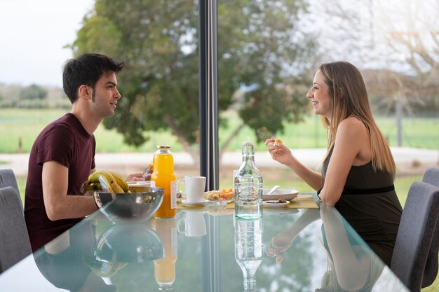 Intimate scene of a young couple having breakfast in the living room of their house near the garden