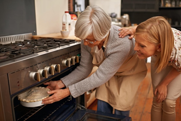 Into the oven Shot of a beautiful young woman learning baking tips from her grandmother