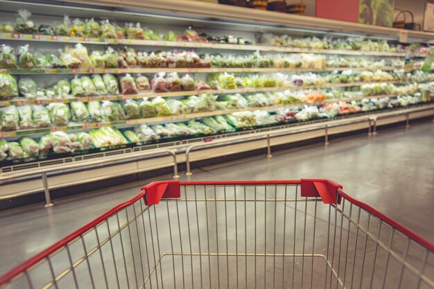 Intreepupil vervagen een winkelwagentje dat boodschappen koopt op de vloer plantaardig voedsel in de supermarkt