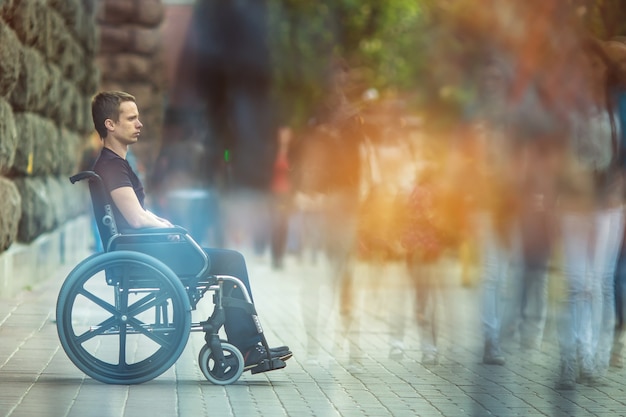 The invalid man sit in the wheel chair in the crowd flow on the street