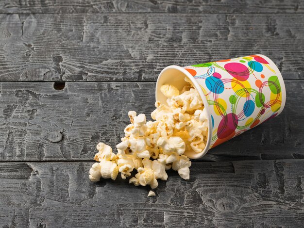 Photo inverted colorful glass of popcorn on a black rustic table.