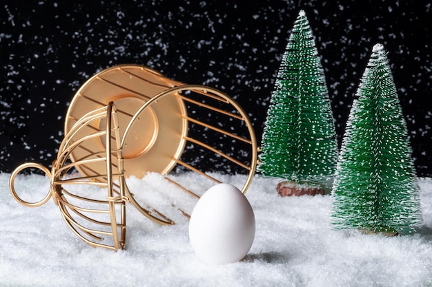 An inverted open cage with an egg outside in a snowy forest at night The concept of change