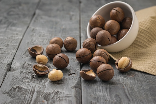 An inverted white ceramic bowl with spilled macadamia nuts on a black table