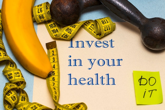 Invest in your health - the inscription on the sheet of paper with dumbbells, banana and roulette