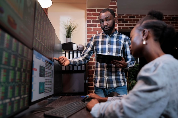 Investment company employees in office workspace conversating\
about possible market crash. financial analysts reviewing real time\
stock prices data in order to gain profits.