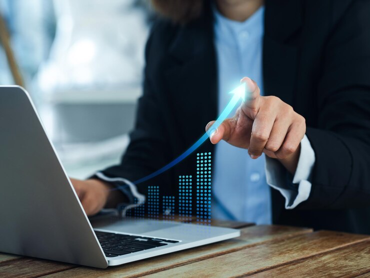 Investment technology financial return on investment ROI concepts Increasing arrow the exponential curve of progress in business performance over charts on laptop draws by businesswoman's hand